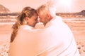 Couple sitting on the beach under blanket smiling at each other Royalty Free Stock Photo