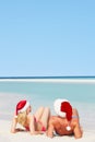 Couple Sitting On Beach Wearing Santa Hats Royalty Free Stock Photo