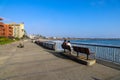 A couple sitting on a bench at the beach with vast blue ocean water and hotels along the beach at Surfers Point at Seaside Park