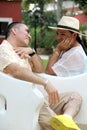 Couple sitting on a bench confidant chairs in Merida in Yucatan Mexico show their love with flirtatious looks and kisses