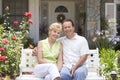 Couple Sitting On Bench Outside House