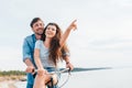 couple sitting on bicycle on beach while girl