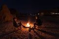 Couple sitting at burning camp fire in the night. Camping in the desert with wild elephants in background. Summer adventures and e Royalty Free Stock Photo