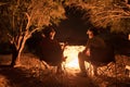 Couple sitting at burning camp fire in the night. Camping in the forest under starry sky, Namibia, Africa. Summer adventures and e Royalty Free Stock Photo