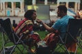 couple sitting in camp-chairs in city park looking movie outdoors at open air cinema