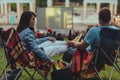 couple sitting in camp-chairs in city park looking movie outdoors at open air cinema