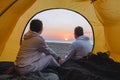 couple sitting in camping tent looking at sunset