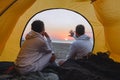 couple sitting in camping tent looking at sunset