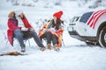 couple sitting in chairs near campfire talking. suv car with usa flag on the hood Royalty Free Stock Photo