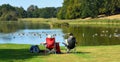 Couple sitting on chairs viewing a lake with ducks and trees