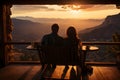 A couple sitting in chairs watching the sunset over mountains