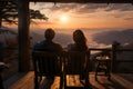 A couple sitting in chairs watching the sunset over mountains