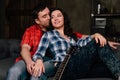 Couple is sitting on the couch with a guitar. Long hair of a brunette with an acoustic guitar.