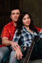 Couple is sitting on the couch with a guitar. Long hair of a brunette with an acoustic guitar.