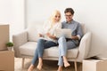 Couple sitting on couch reading design project documents on laptop