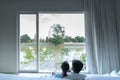 Couple sitting on daybed and looking through the window in their new apartment with fantastic river view / moving house /