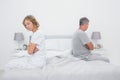 Couple sitting on different sides of bed not talking after fight Royalty Free Stock Photo