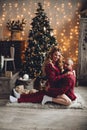 Couple sitting embraced at Christmas tree.