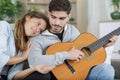 couple sitting and embracing on couch while man playing guitar Royalty Free Stock Photo