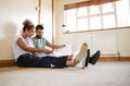 Couple Sitting On Floor Looking At Plans In Empty Room Of New Home Royalty Free Stock Photo