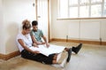 Couple Sitting On Floor Looking At Plans In Empty Room Of New Home Royalty Free Stock Photo