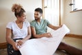 Couple Sitting On Floor Looking At Plans In Empty Room Of New Home Royalty Free Stock Photo