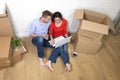 Couple sitting on floor moving in a new house or apartment flat using computer laptop Royalty Free Stock Photo