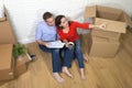 Couple sitting on floor moving in a new house or apartment flat using computer laptop Royalty Free Stock Photo