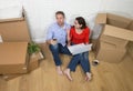 Couple sitting on floor moving in a new house or apartment flat using computer laptop Royalty Free Stock Photo
