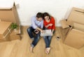 couple sitting on floor moving in new house choosing furniture with computer laptop Royalty Free Stock Photo