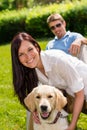 Couple sitting with golden retriever in park Royalty Free Stock Photo