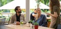 Couple sitting outdoors on terrace restaurant, ordering food from a waiter. Business lunch for two managers, discussing Royalty Free Stock Photo