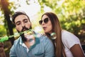 Couple sitting on the park bench and blowing soup bubbles