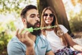 Couple sitting on the park bench and blowing soup bubbles on beautiful day Royalty Free Stock Photo