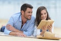 couple sitting and reading on terrace near water Royalty Free Stock Photo