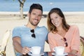 Couple sitting at restaurant with ocean view drinking coffee