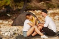 Couple sitting at rocky beach with iron cups of tea in hand. Royalty Free Stock Photo