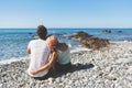 Couple sitting on rocky beach looking at sea Royalty Free Stock Photo