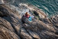 couple sitting on rocky edge to Mediterranean in sun