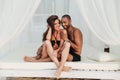 Couple sitting and smiling in white bed on the beach Royalty Free Stock Photo