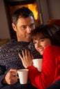 Couple Sitting On Sofa By Cosy Log Fire Royalty Free Stock Photo