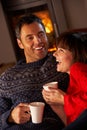 Couple Sitting On Sofa By Cosy Log Fire Royalty Free Stock Photo