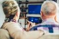 Couple sitting on a sofa holding remote home control system on a digital tablet Royalty Free Stock Photo