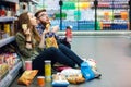Couple sitting on the supermarket floor and eating snacks Royalty Free Stock Photo