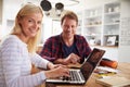 Couple sitting in their kitchen using computers Royalty Free Stock Photo