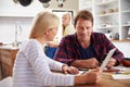 Couple sitting in their kitchen using computers Royalty Free Stock Photo