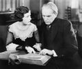 Couple sitting together and looking at a book with a worried facial expression