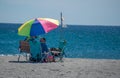 A couple sitting under an umbrella on the sand on a beach in Florida Royalty Free Stock Photo
