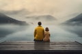 Couple sitting on a wooden pier and looking at a lake in the fog, Family with a small yellow dog resting on a pier and looking at Royalty Free Stock Photo