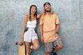 Couple With Skateboards Portrait. Happy Guy And Girl In Casual Outfit Against Concrete Wall At Skatepark. Urban Subculture And